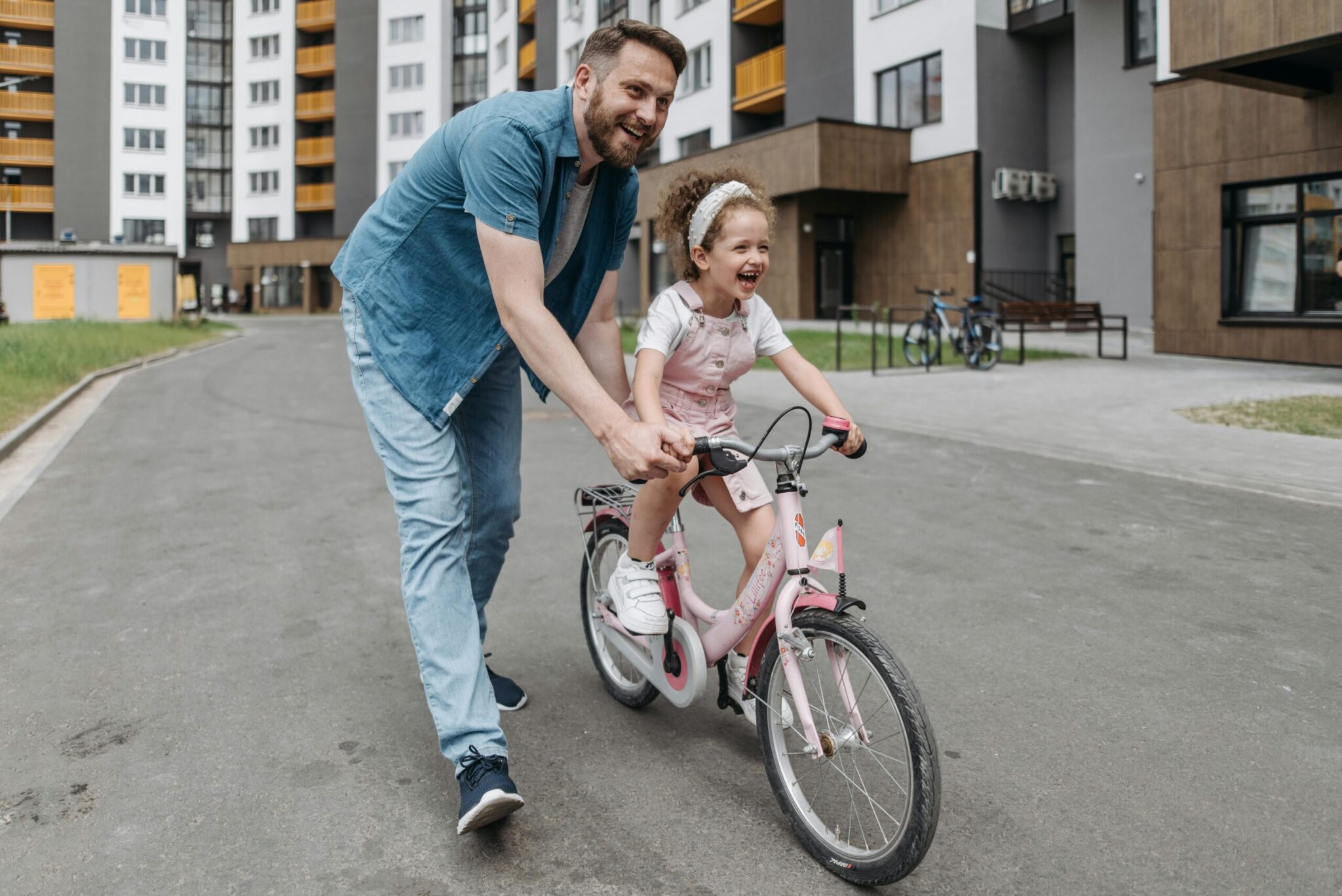 Father helping his young daughter ride a bicycle in a residential neighborhood