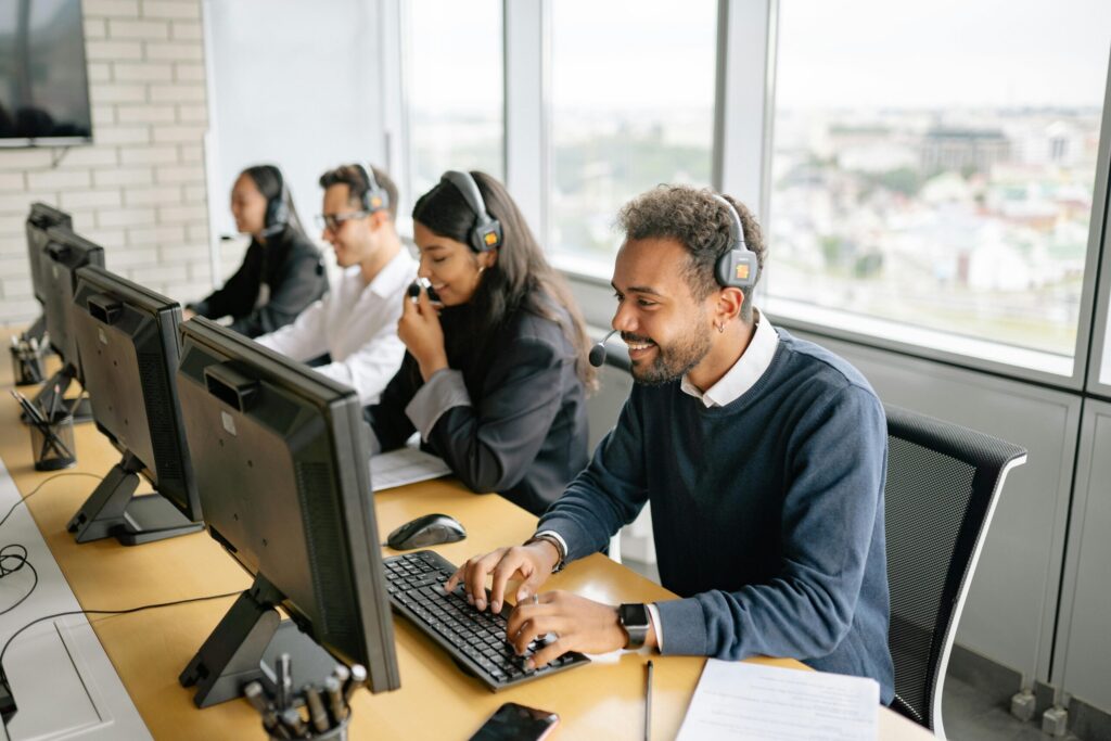 Customer support team working in call center with headsets and computers